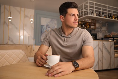 Photo of Man with cup of coffee at cafe in morning