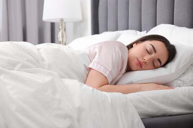 Beautiful young woman sleeping in soft bed at home