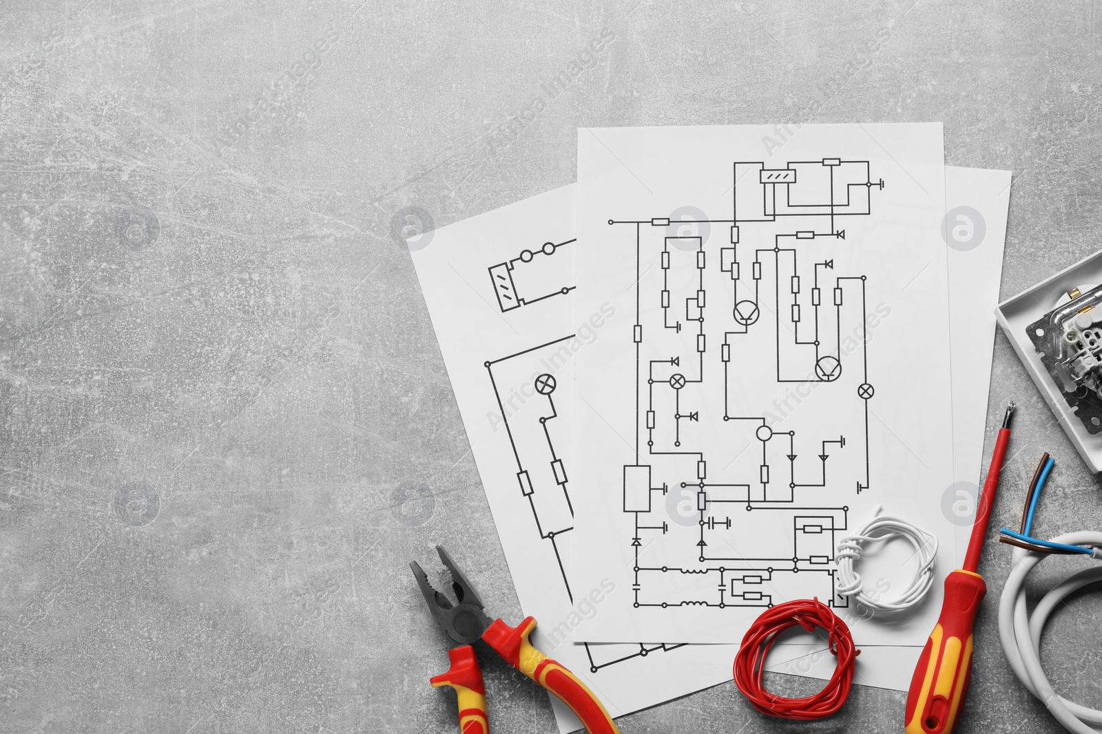 Photo of Wiring diagrams, wires and tools on grey table, flat lay. Space for text