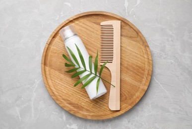 Photo of Dry shampoo spray, green twig and comb on light grey marble table, top view