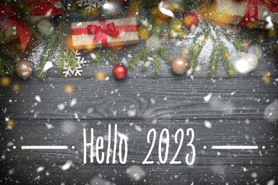 Hello 2023. Flat lay composition with fir tree branches and festive decor on black wooden background