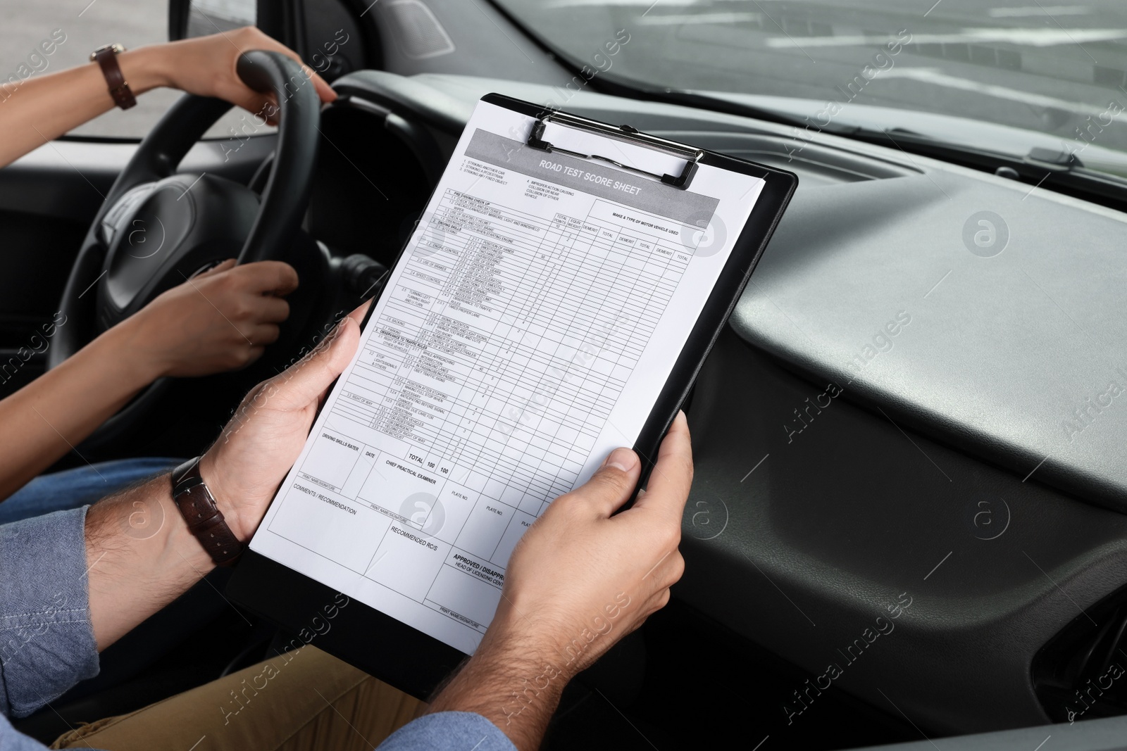 Photo of Driving school. Student passing driving test with examiner in car at parking lot, closeup