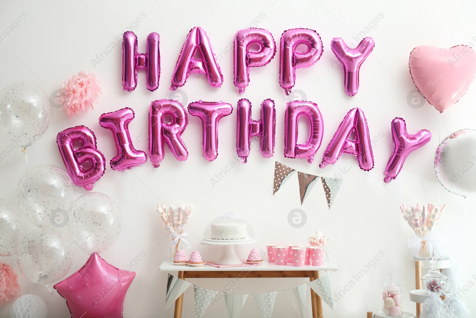 Photo of Phrase HAPPY BIRTHDAY made of pink balloon letters on white wall