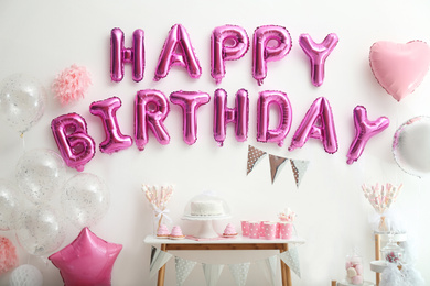 Phrase HAPPY BIRTHDAY made of pink balloon letters on white wall