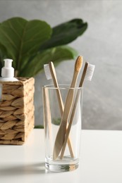 Photo of Bamboo toothbrushes in glass holder on white countertop