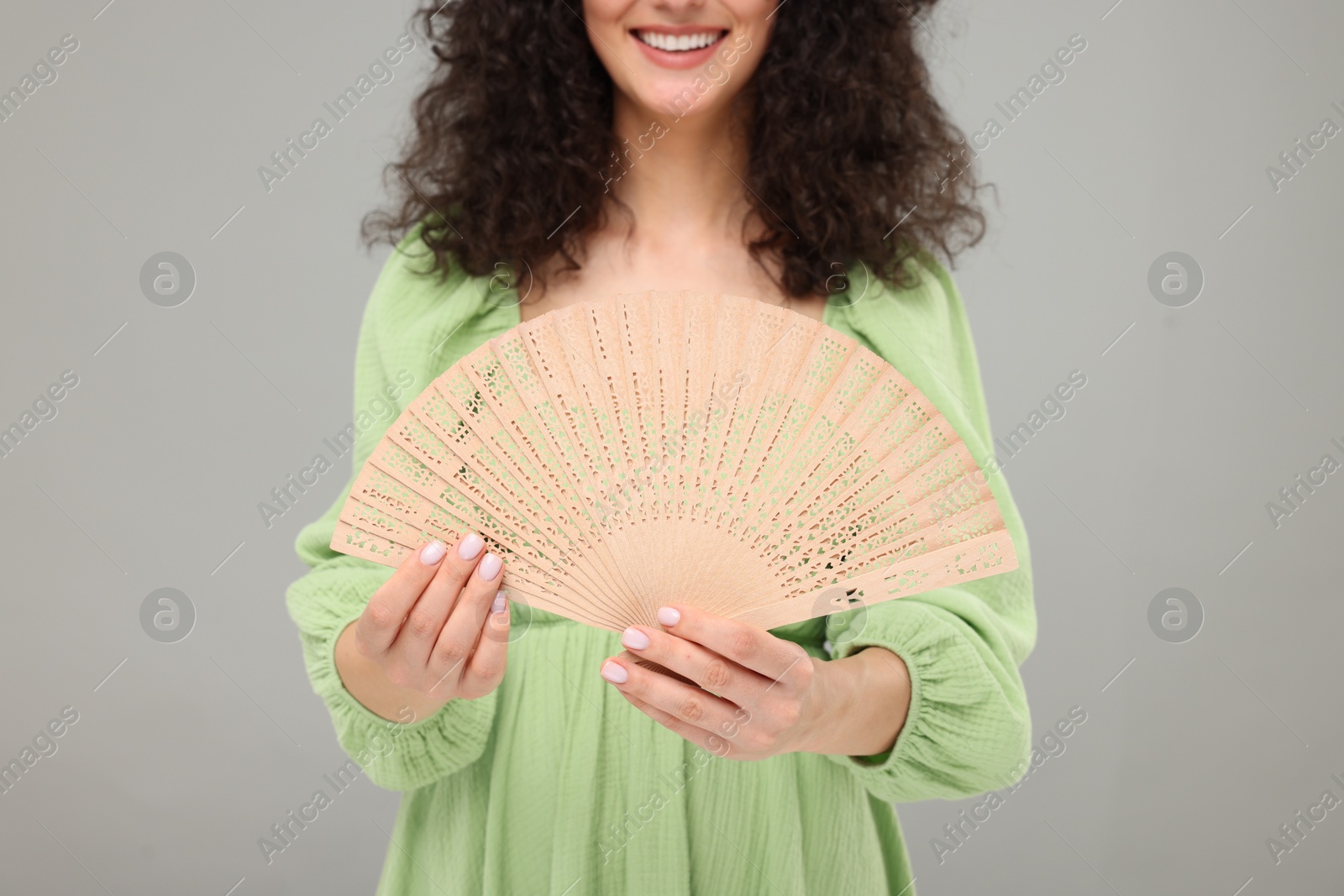 Photo of Woman holding hand fan on light grey background, closeup