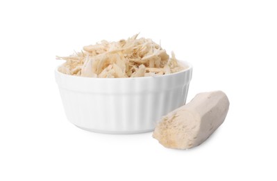 Grated horseradish in bowl and peeled root isolated on white