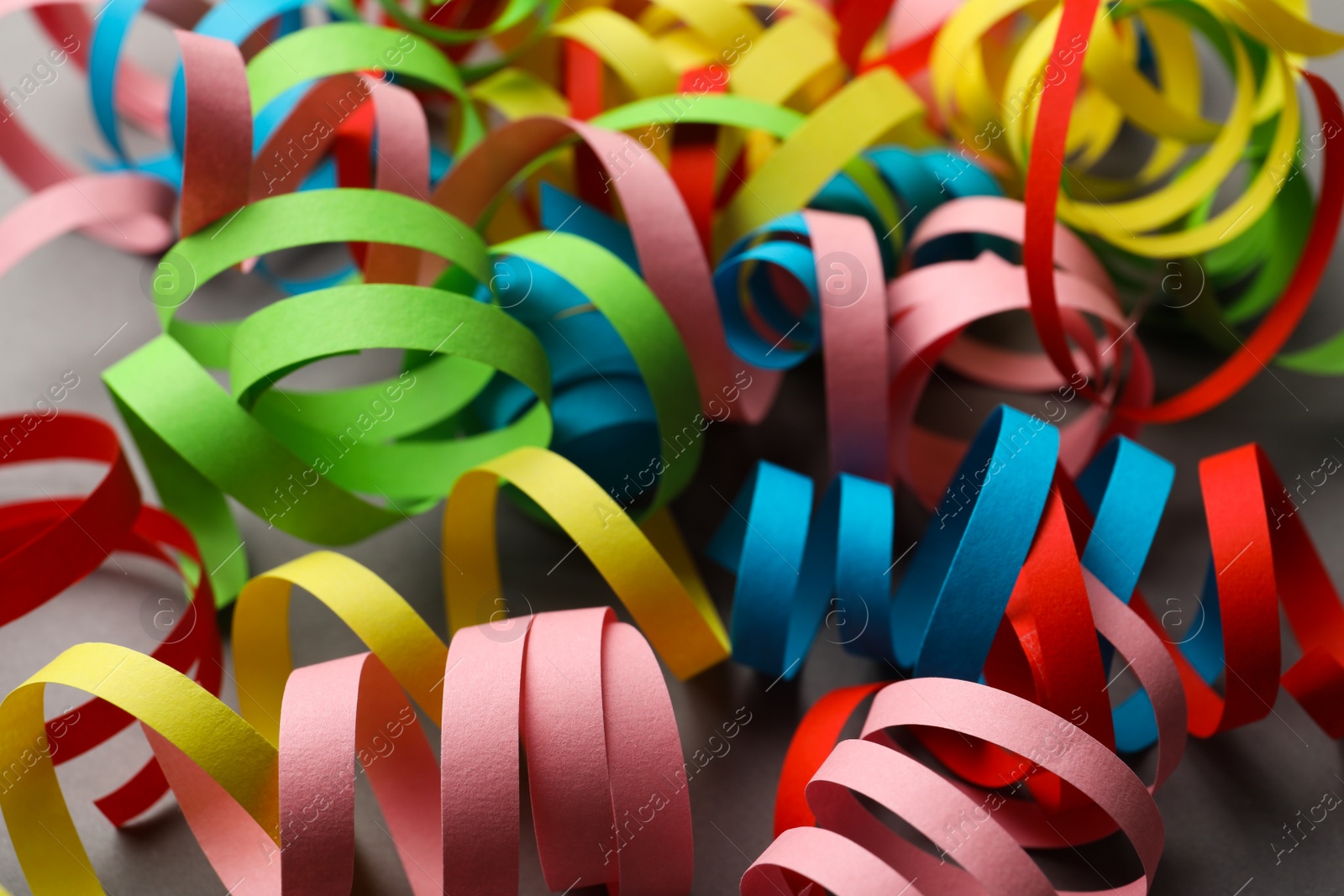 Photo of Colorful serpentine streamers on grey background, closeup