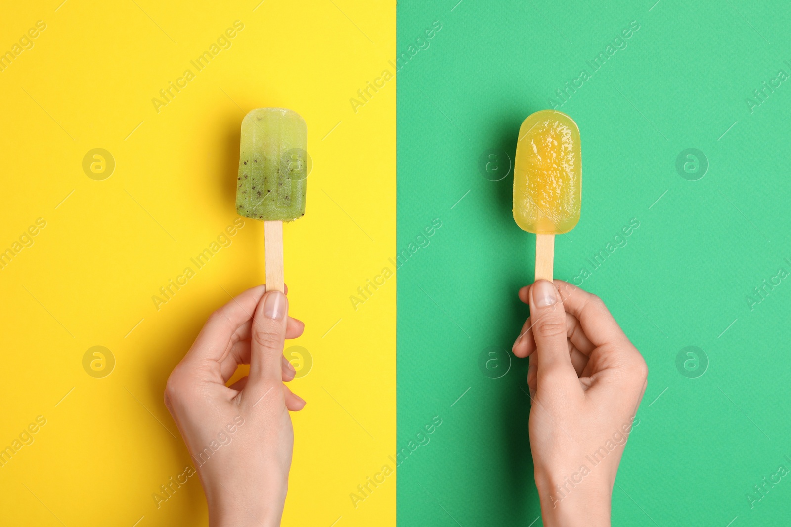 Photo of Woman holding delicious ice pops on color background, top view. Fruit popsicle