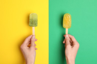 Photo of Woman holding delicious ice pops on color background, top view. Fruit popsicle
