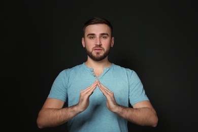 Photo of Man showing HOUSE gesture in sign language on black background