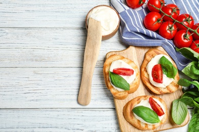 Photo of Flat lay composition of bruschettas with cheese, basil and tomatoes on white wooden table, space for text
