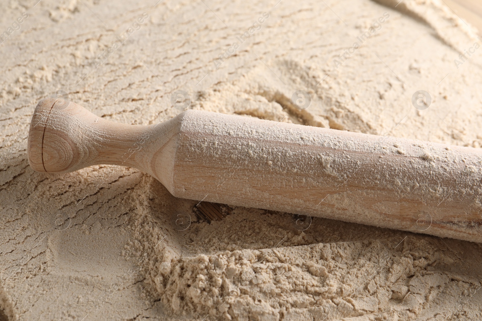 Photo of Flour and rolling pin on table, closeup