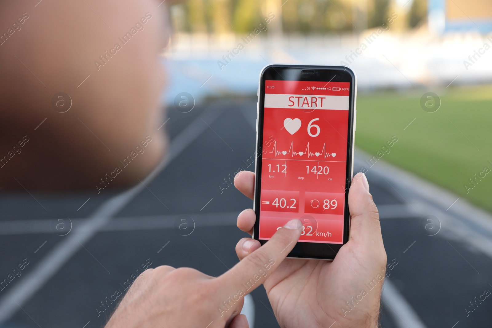 Photo of Man using fitness app on smartphone at stadium, closeup