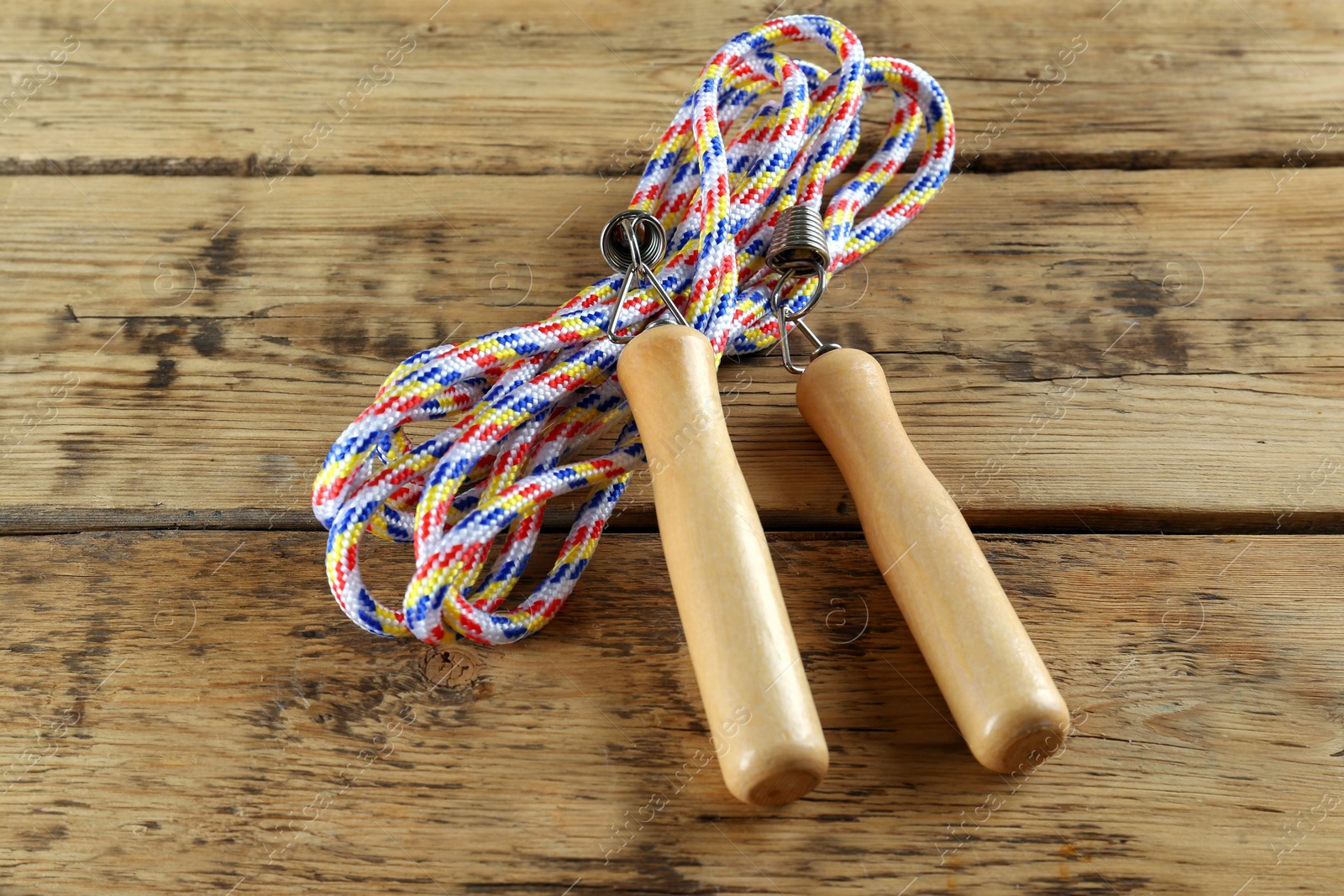 Photo of Skipping rope on wooden table, closeup. Sports equipment