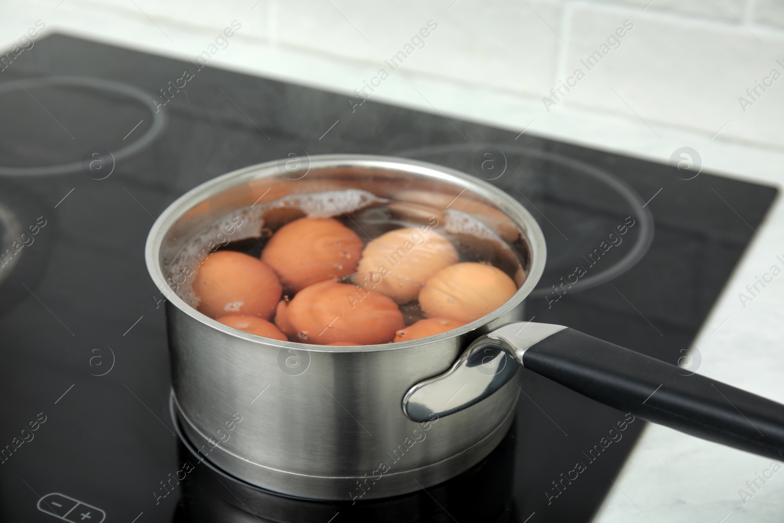 Photo of Boiling chicken eggs in saucepan on electric stove