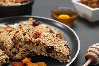 Photo of Tasty granola bars on grey table, closeup