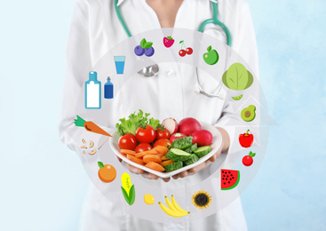 Nutritionist's recommendations. Doctor with healthy products on light blue background, closeup