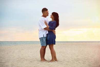 Happy mature couple spending time together on sea beach at sunset