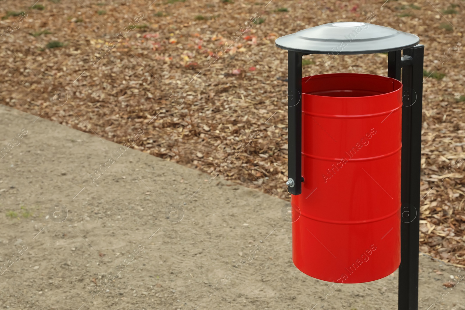 Photo of Red metal trash bin outdoors. Space for text