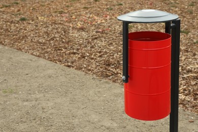 Photo of Red metal trash bin outdoors. Space for text