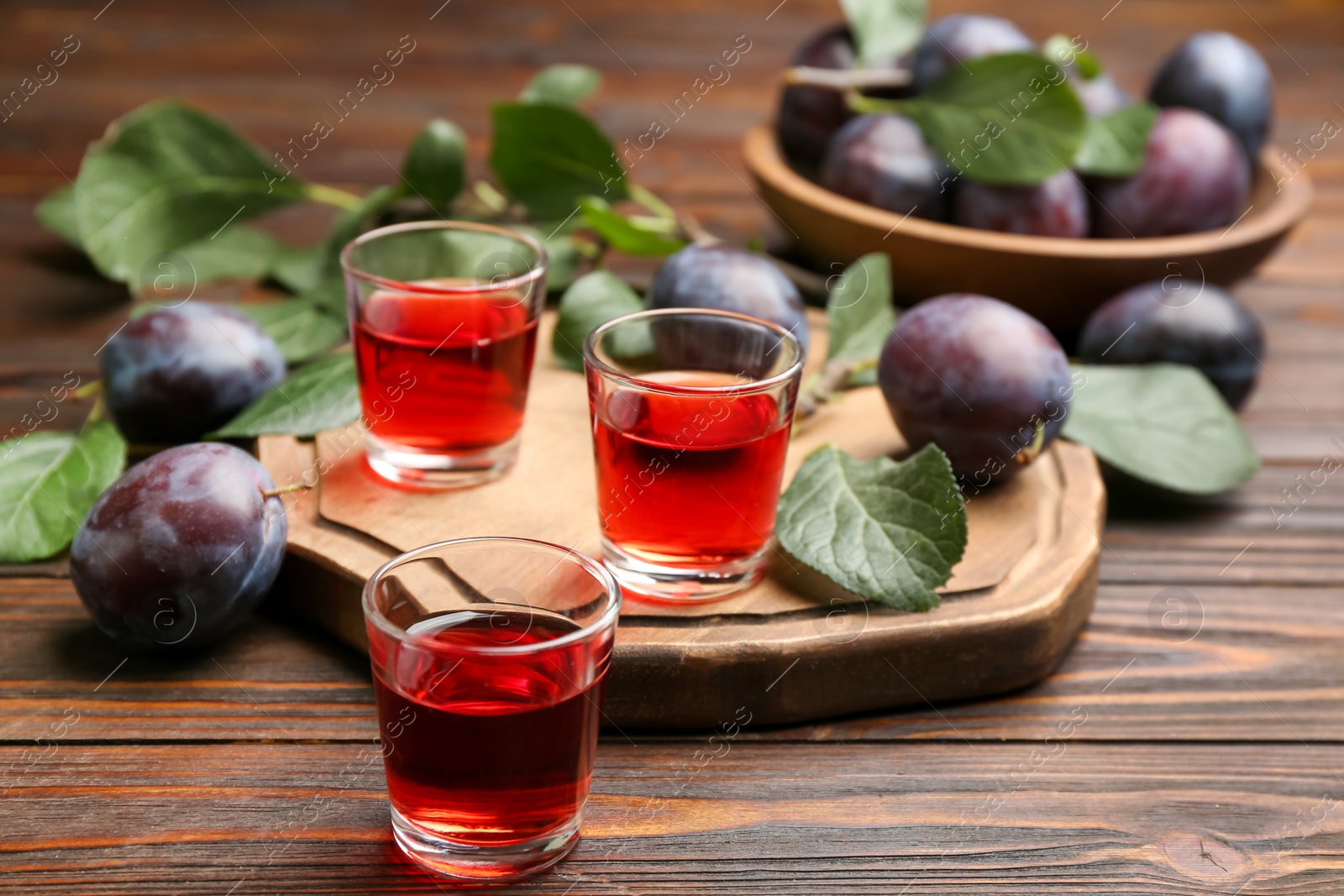 Photo of Delicious plum liquor and ripe fruits on wooden table. Homemade strong alcoholic beverage