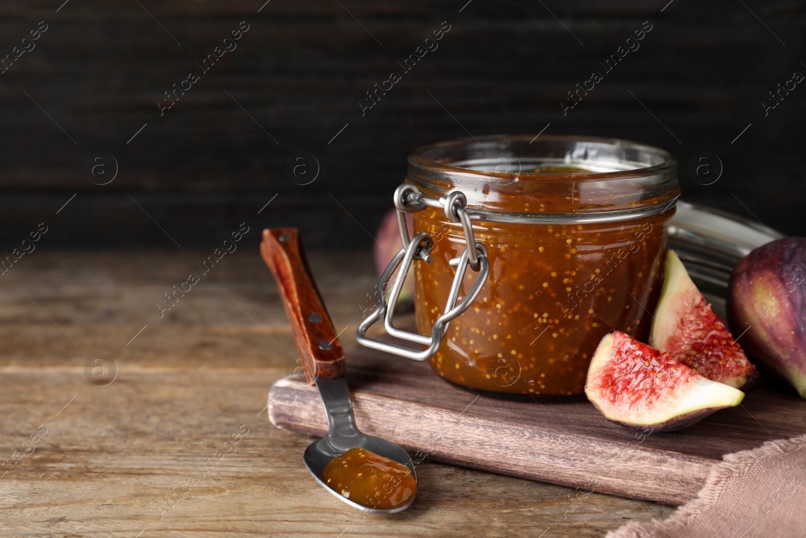 Photo of Homemade delicious fig jam and fresh fruits on wooden table. Space for text