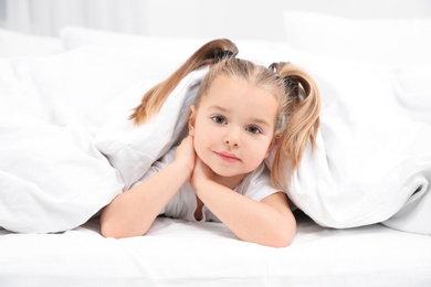 Photo of Beautiful little girl in bed at home. Bedtime schedule