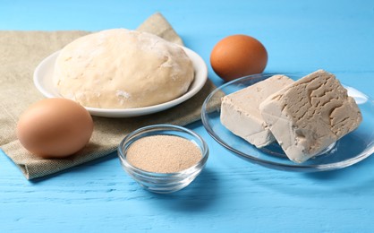 Photo of Different types of yeast, eggs and dough and on light blue wooden table