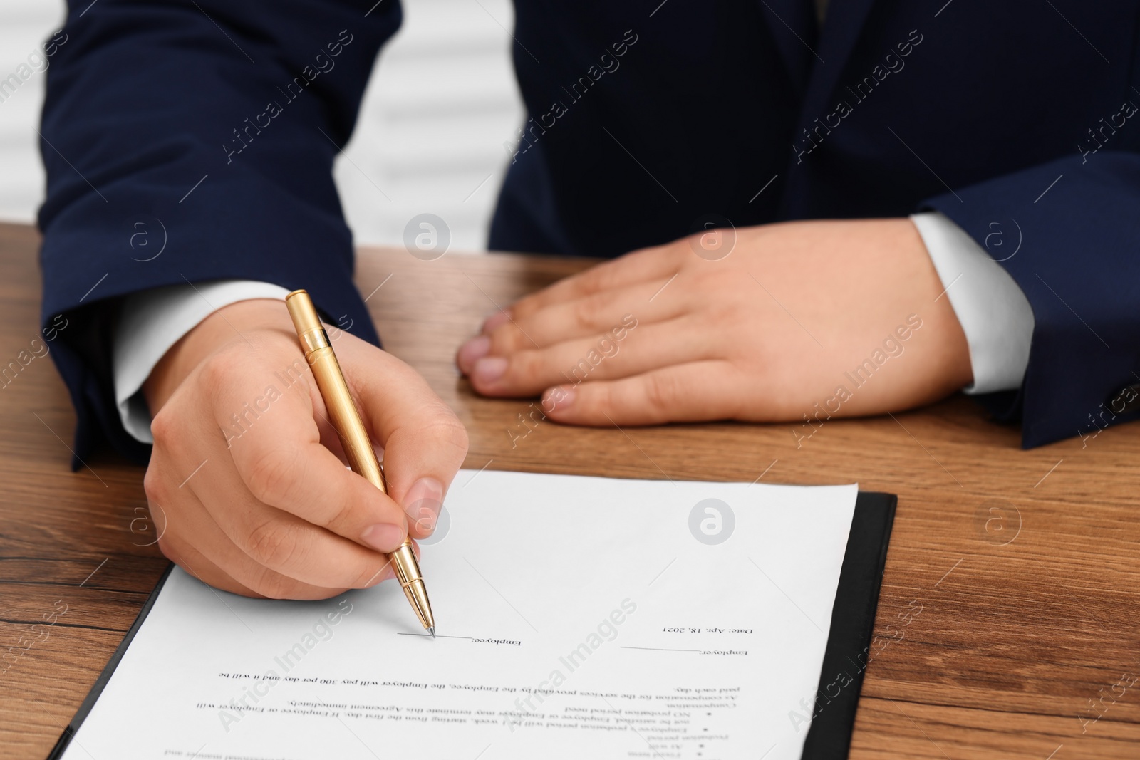 Photo of Man signing document at wooden table, closeup