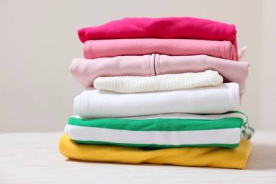 Photo of Stack of folded clothes on table against beige background