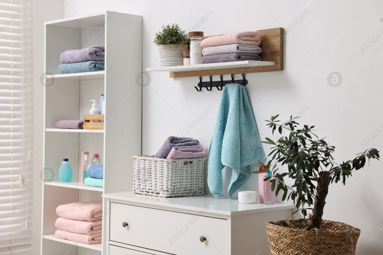 Photo of Fresh towels, laundry basket and toiletries on chest of drawers indoors