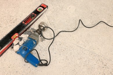 Buffing attachment drill and building level on floor. Tiles installation process