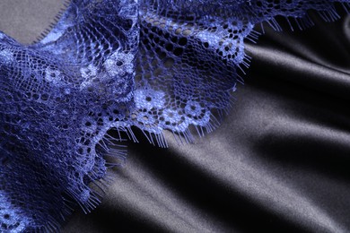 Photo of Beautiful blue lace on black fabric, top view