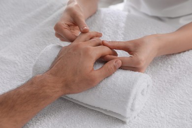 Photo of Man receiving hand massage on soft towel, closeup