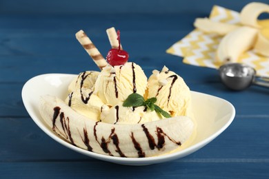 Photo of Delicious dessert with banana ice cream on blue wooden table