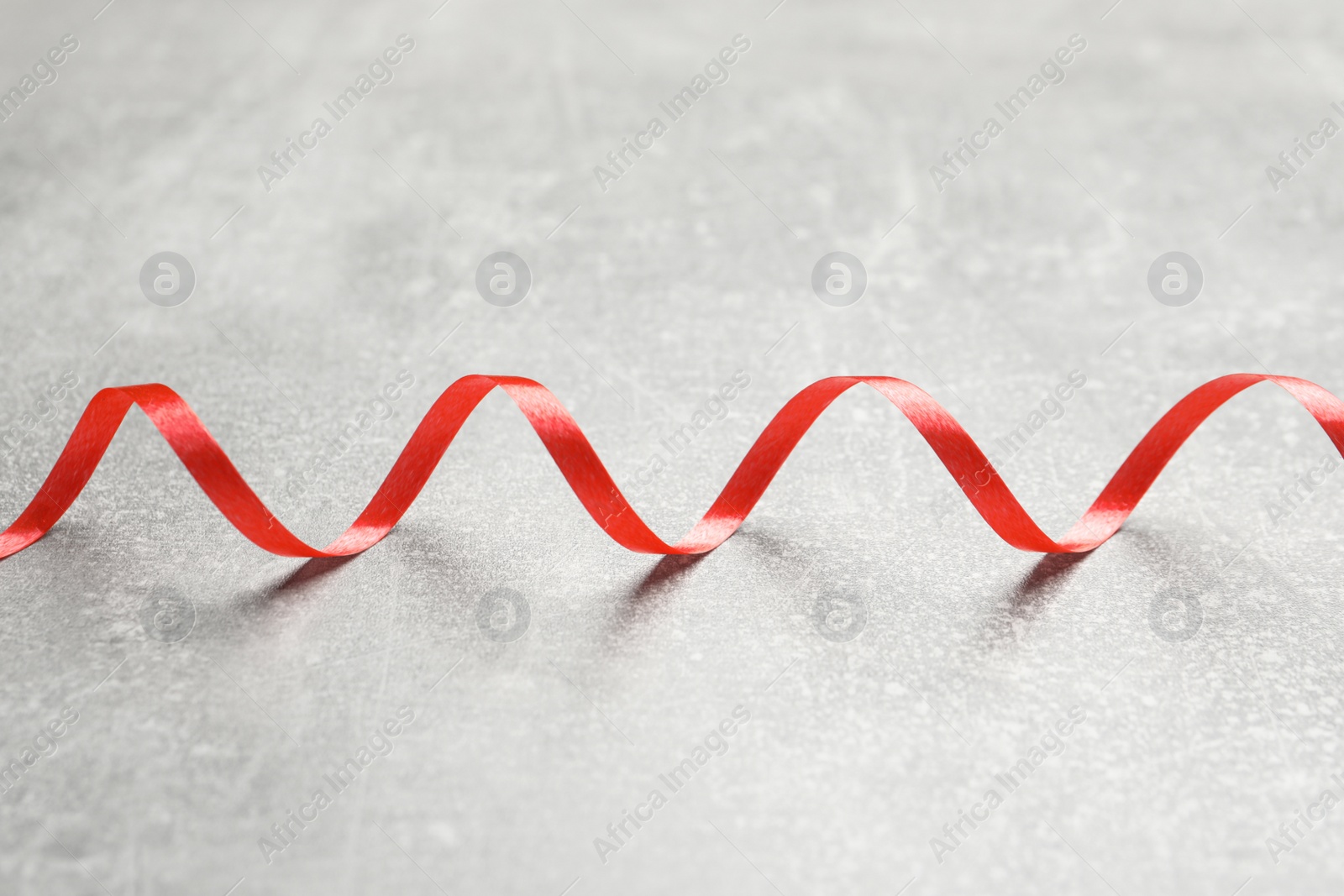 Photo of Shiny red serpentine streamer on grey background