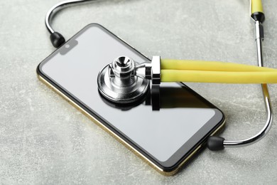 Stethoscope and modern smartphone on grey table