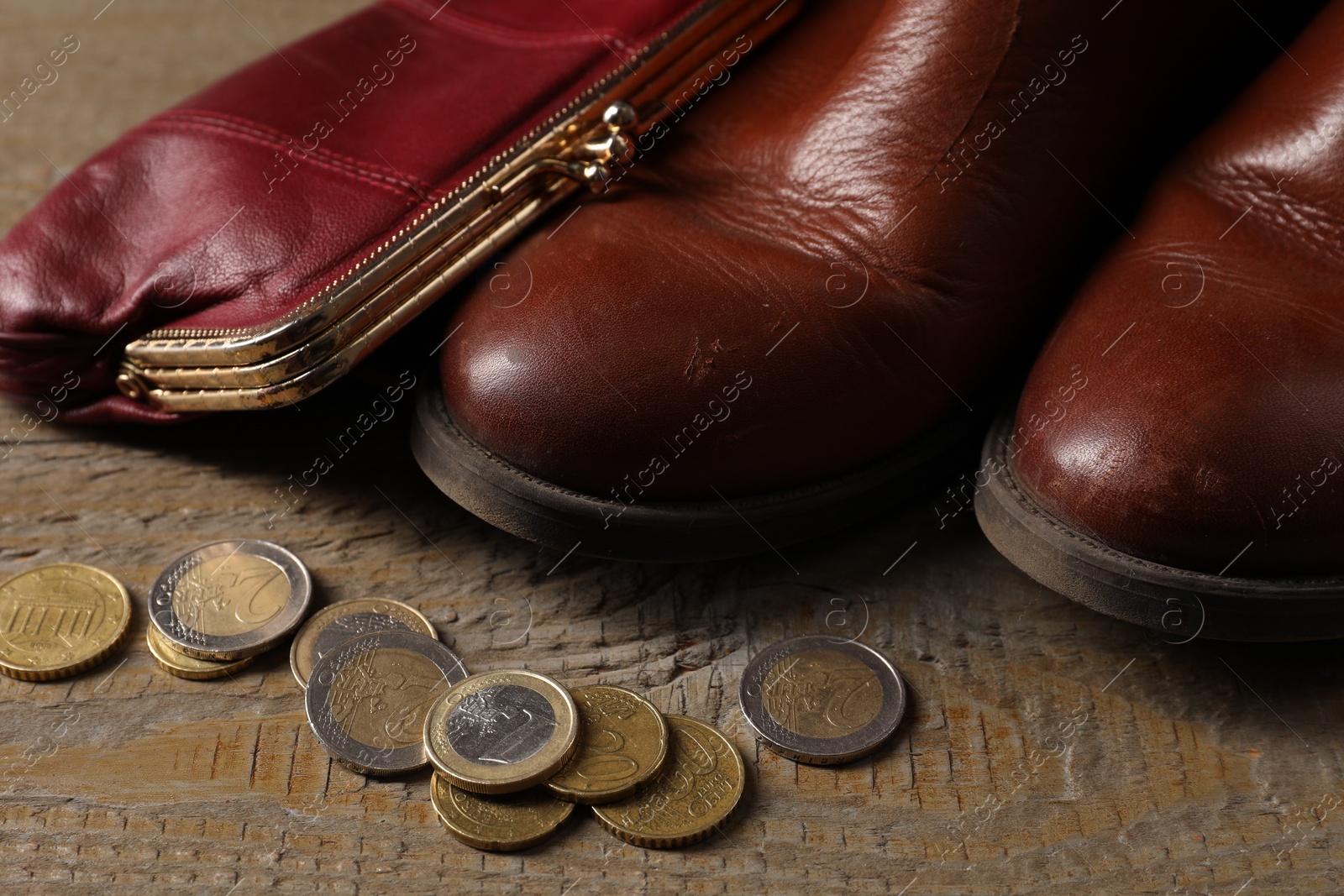 Photo of Poverty. Old boots, wallet and coins on wooden table, closeup