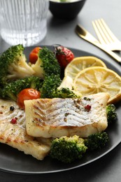 Photo of Tasty cod cooked with vegetables served on grey table, closeup