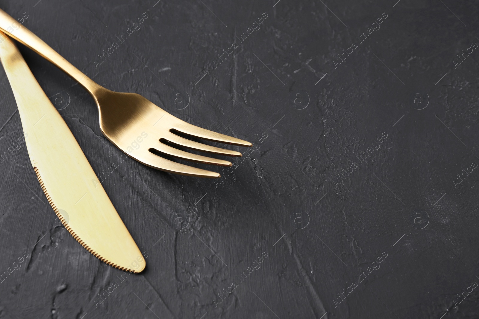 Photo of Beautiful cutlery set on black table, closeup. Space for text