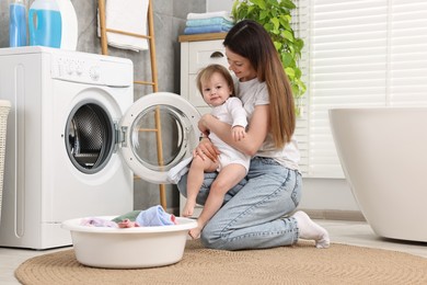 Photo of Mother with her daughter washing baby clothes in bathroom