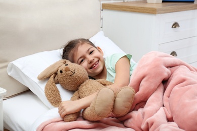 Cute child with stuffed bunny resting in bed at hospital