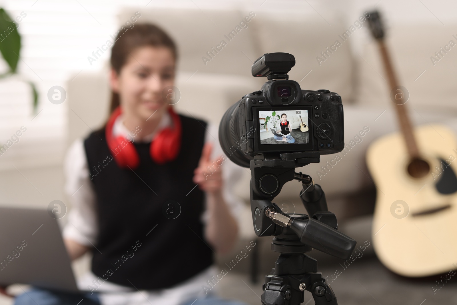 Photo of Teenage blogger explaining something while streaming at home, focus on camera