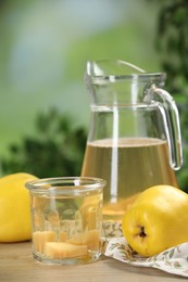 Photo of Delicious quince drink and fresh fruits on wooden table against blurred background