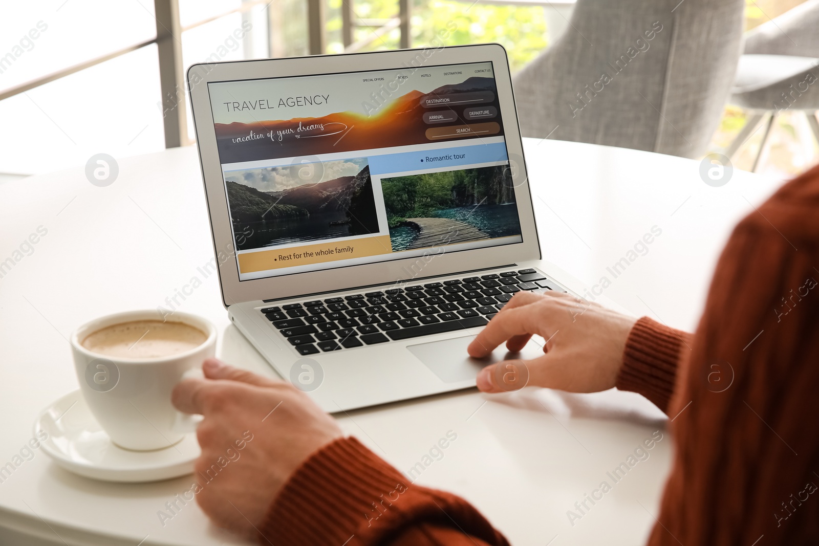 Photo of Man booking tickets online on laptop at white table, closeup. Travel agency concept