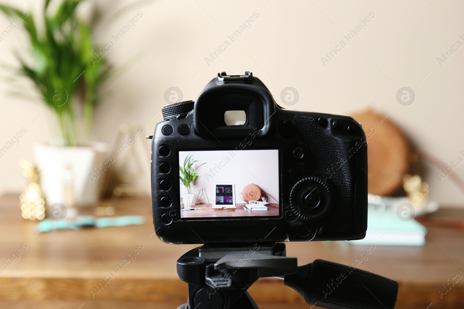 Photo of Camera with photo of stylish workplace on screen indoors, selective focus. Fashion blogger