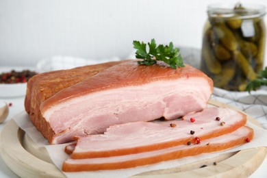 Photo of Delicious smoked bacon with parsley and peppercorns on wooden plate, closeup