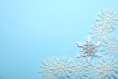 Photo of Beautiful decorative snowflakes on light blue background, flat lay. Space for text