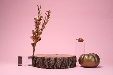 Stylish presentation for product. Wooden stump, geometric figures and autumn decor on pink background